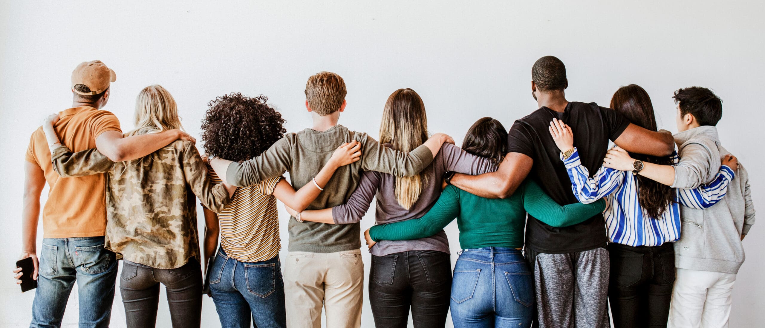 Rearview,Of,Diverse,People,Hugging,Each,Other Group of people standing in a line, holding each other